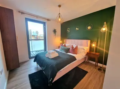 a bedroom with a bed with a green wall at Luxury Station Apartment in Cambridge