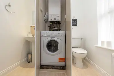 a bathroom with a washing machine and a toilet at Luxury Station Apartment in Cambridge