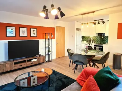 a living room with a television and a table and chairs at Luxury Station Apartment in Cambridge