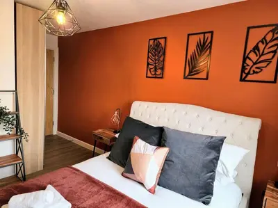 a bedroom with an orange wall and a bed with pillows at Luxury Station Apartment in Cambridge