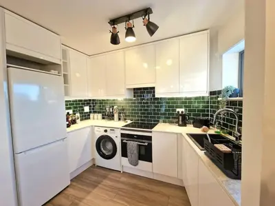a kitchen with white cabinets and a washer and dryer at Luxury Station Apartment in Cambridge