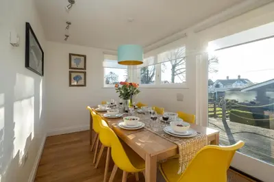 a dining room with a wooden table and yellow chairs at 9 Uplands in Thorpeness