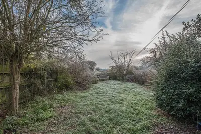 a field of grass with a fence and trees at Jenny Rose Cottage, Wickham Market in Woodbridge