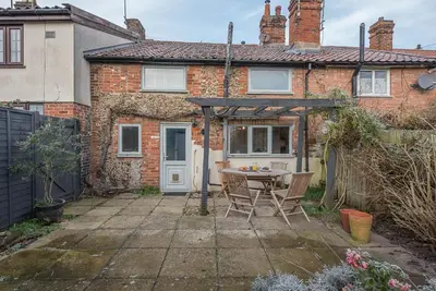 a patio with a table and chairs in front of a house at Jenny Rose Cottage, Wickham Market in Woodbridge