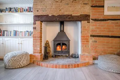 a brick fireplace with a stove in a room at Jenny Rose Cottage, Wickham Market in Woodbridge