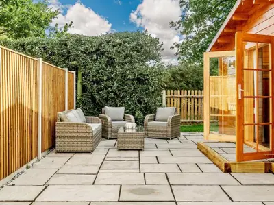 a patio with couches and chairs and a fence at Hulver Lodge, Snape, Suffolk. in Snape