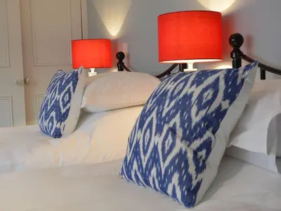 a bed with blue and white pillows and two lamps at Crabbe Corner in Aldeburgh