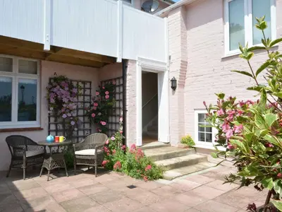 a patio with a table and chairs and flowers at Crabbe Corner in Aldeburgh