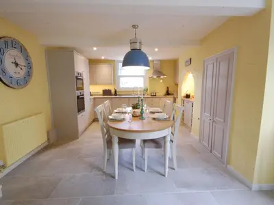a kitchen with a table and chairs and a clock at Crabbe Corner in Aldeburgh