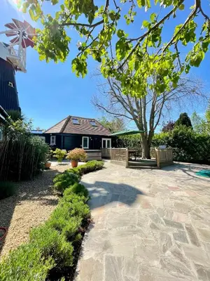 a house with a tree and a stone patio at The Millers Cottage in Cambridge