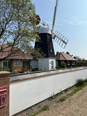 a house with a windmill behind a white wall at The Millers Cottage in Cambridge