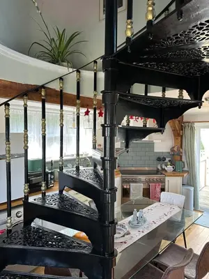 a black spiral staircase in a room with a table at The Millers Cottage in Cambridge