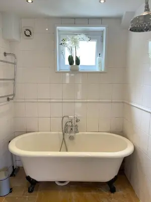 a white bath tub in a bathroom with a window at Cosy Courtyard Cottage sleeps 4 with Log Burner, close to Cambridge in Cambridge