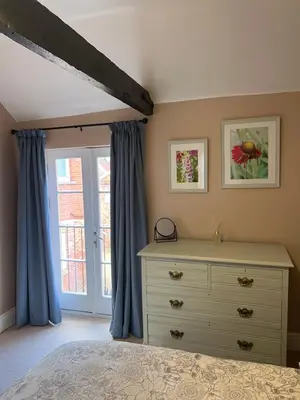 a bedroom with a bed and a dresser and a window at The Barn in Saxmundham