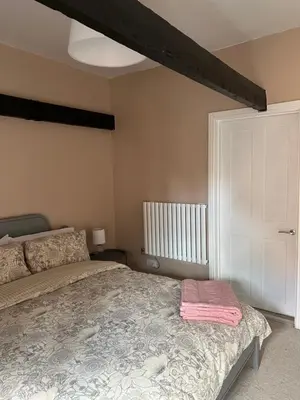 a bedroom with a bed with a pink blanket on it at The Barn in Saxmundham
