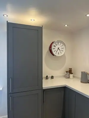 a clock on the wall next to a kitchen counter at The Barn in Saxmundham
