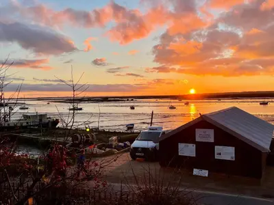 a sunset over a body of water with boats at Cosy Coastal 2-Bedroom Cottage with Hot Tub and Log Burner in West Mersea