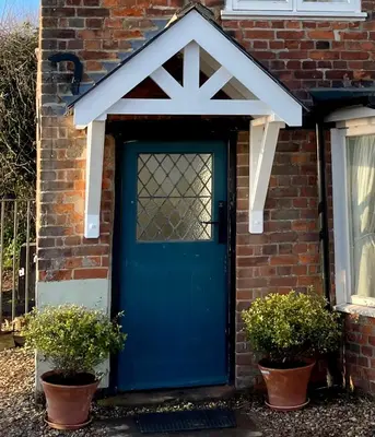 a blue door on a brick house with two potted plants at Cosy Coastal 2-Bedroom Cottage with Hot Tub and Log Burner in West Mersea