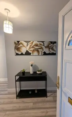 a room with a table with flowers on a wall at A&A Apartment Basildon in Nevendon