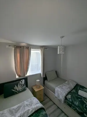a small bedroom with two beds and a window at A&A Apartment Basildon in Nevendon