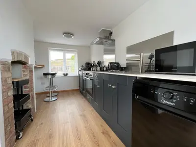 a kitchen with gray cabinets and a counter top at Dolls House Cottage in Hilborough
