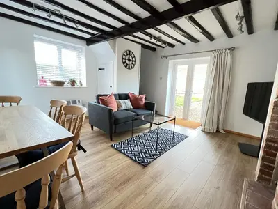 a living room with a couch and a table at Dolls House Cottage in Hilborough