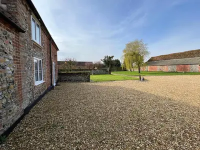 a brick building with a gravel driveway next to it at Dolls House Cottage in Hilborough