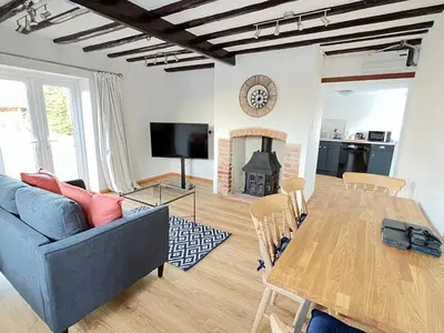 a living room with a blue couch and a table at Dolls House Cottage in Hilborough