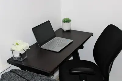 a black desk with a laptop and two chairs at Lovely Modern Apartment Close to Town Centre in Lexden