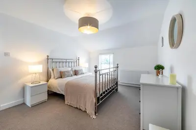 a white bedroom with a bed and a window at Sea Breeze Apartment in Walton-on-the-Naze