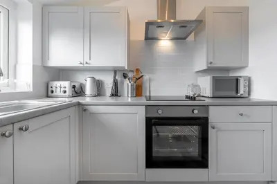 a kitchen with white cabinets and a stove top oven at Sea Breeze Apartment in Walton-on-the-Naze