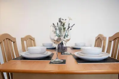 a wooden table with plates and a wine glass at King's - Spacious Central Ground Floor Apartment in Cambridge