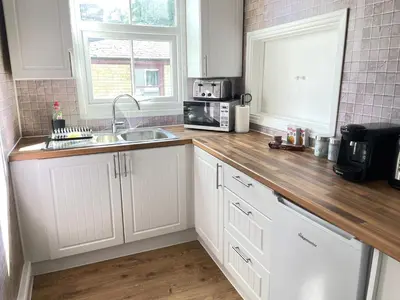 a kitchen with white cabinets and a wooden counter top at King's - Spacious Central Ground Floor Apartment in Cambridge