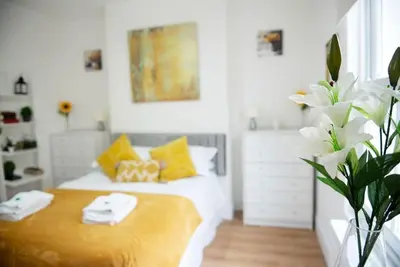 a bedroom with a bed with yellow and white pillows at King's - Spacious Central Ground Floor Apartment in Cambridge