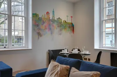 a living room with a blue couch and a table at New London Life Executive Apartments in Chelmsford