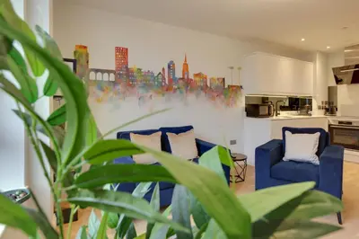 a living room with two blue chairs and a painting on the wall at New London Life Executive Apartments in Chelmsford
