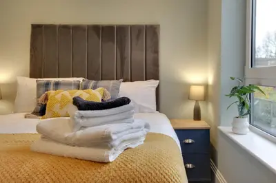 a bedroom with a bed with towels on it at New London Life Executive Apartments in Chelmsford