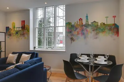 a living room with a blue couch and a table at New London Life Executive Apartments in Chelmsford