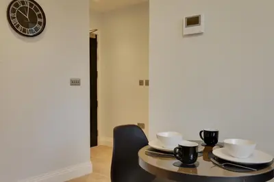 a dining room table with two chairs and a clock at New London Life Executive Apartments in Chelmsford