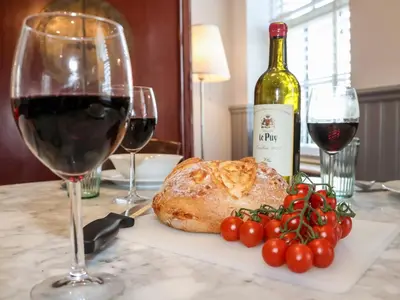 a glass of wine next to a piece of meat and tomatoes at Ebenezer Chapel in Saxmundham