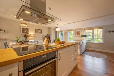 a kitchen with a counter top and a living room at Bell Tower Cottage in Middleton