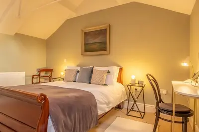 a bedroom with a bed and a table and chairs at Bell Tower Cottage in Middleton