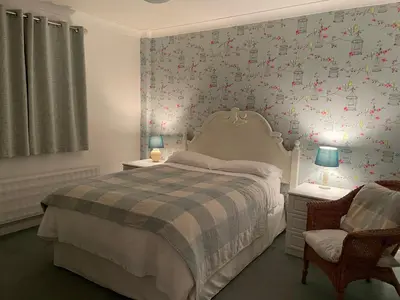 a bedroom with a bed and a wall with flowers at Silver Lodge Guest House in Mildenhall