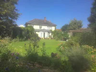 a white house with a garden in front of it at Silver Lodge Guest House in Mildenhall