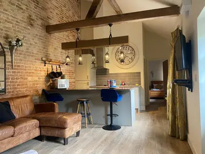 a kitchen and living room with a couch and a bar at Lynford Holiday Cottages nestled in the heart of Thetford Forest in Mundford