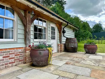 a house with two large flower pots on a patio at Lynford Holiday Cottages nestled in the heart of Thetford Forest in Mundford