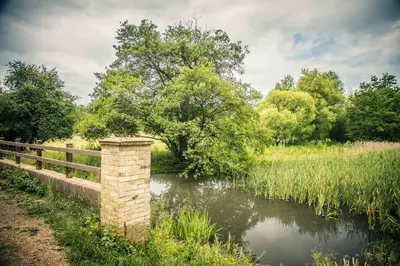 a brick bridge over a river with a fence at Lynford Holiday Cottages nestled in the heart of Thetford Forest in Mundford