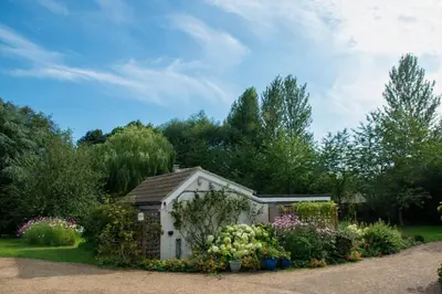 a small greenhouse in a garden with flowers and plants at The Garden Cottage, Wenhaston, Suffolk, near coast in Halesworth