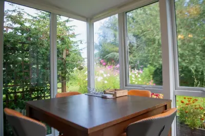 a dining room table with chairs in front of a window at The Garden Cottage, Wenhaston, Suffolk, near coast in Halesworth