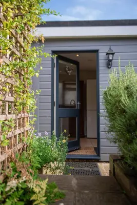 a blue front door of a gray house with flowers at The Garden Cottage, Wenhaston, Suffolk, near coast in Halesworth